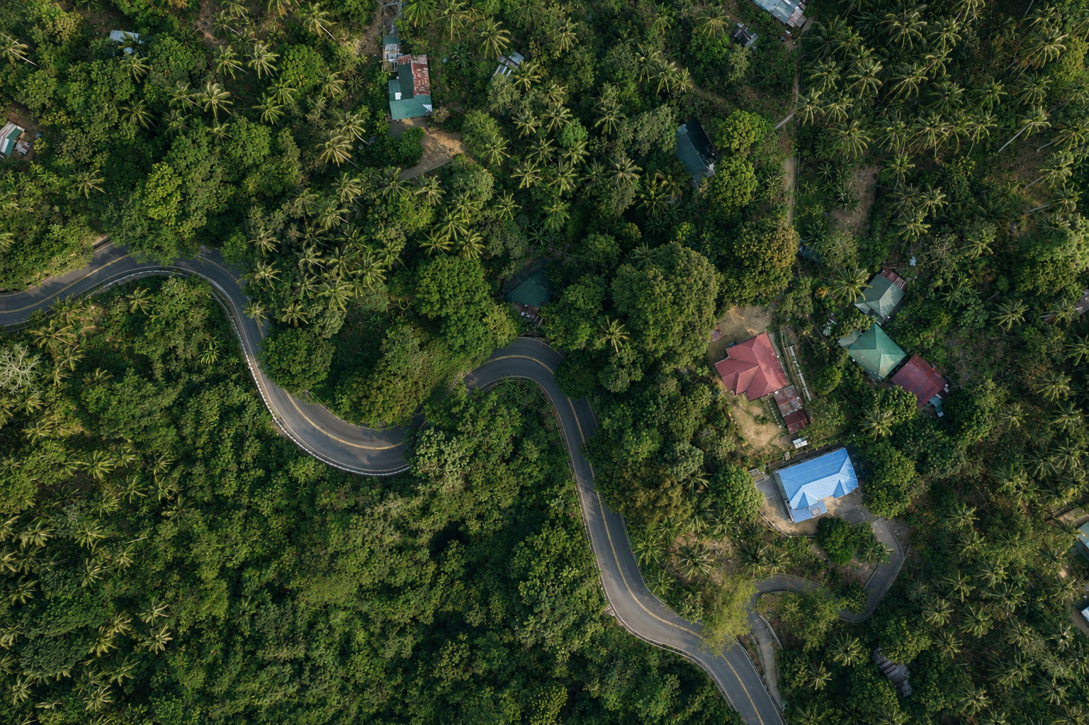 Wide aerial view of the property among tropical greenery and winding roads in Dulangan